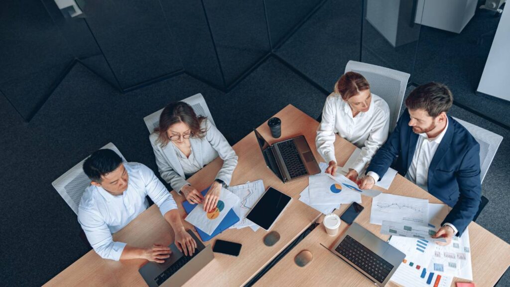 4 mensen overleggend zittend aan een werkbureau